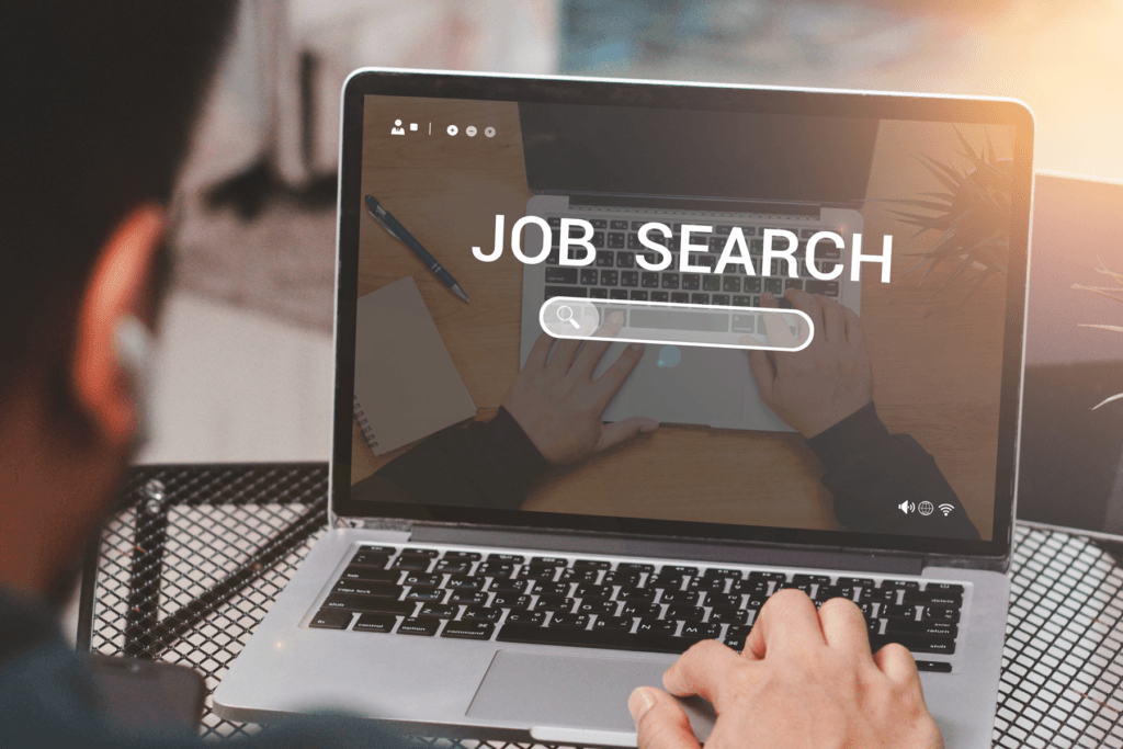 Man sitting at laptop with text displaying "job search", decorative image for job scams